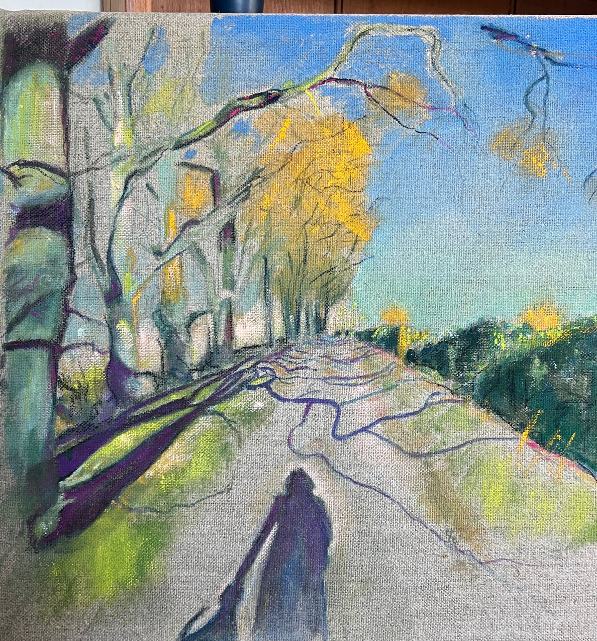 a path lined by Autumn trees with the shadow of a woman and dog